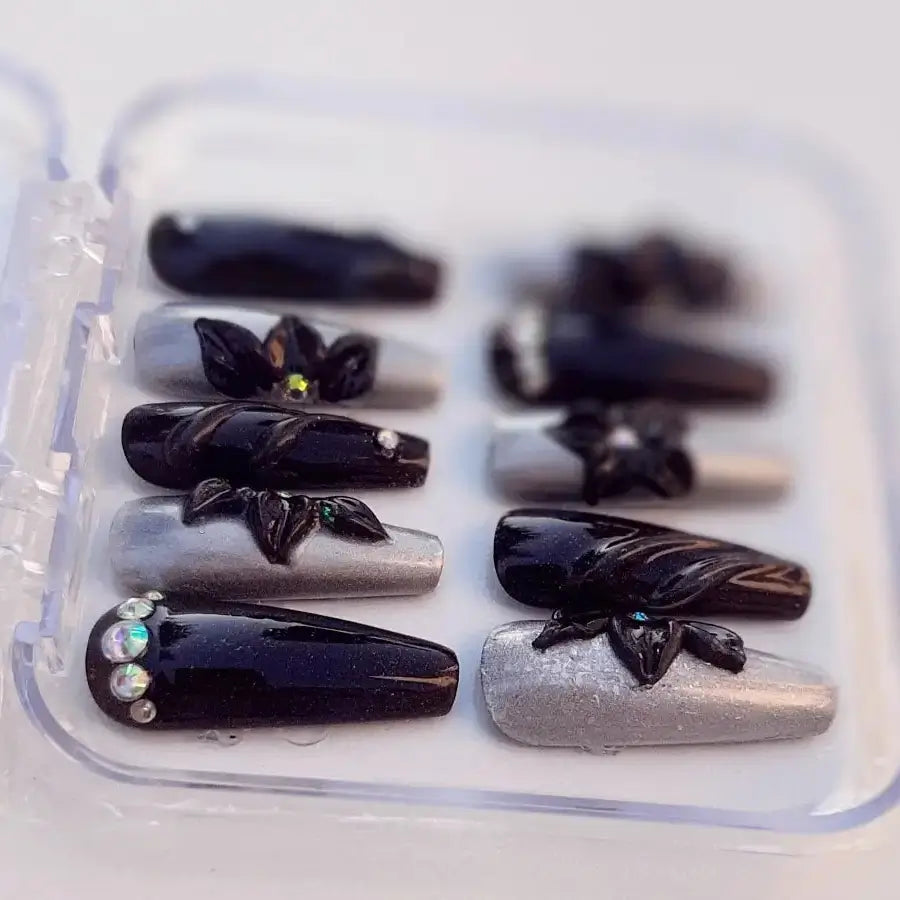 Magnifiques faux ongles de couleur noir et argenté ornés de fleurs 3D et strass pour sublimer vos mains