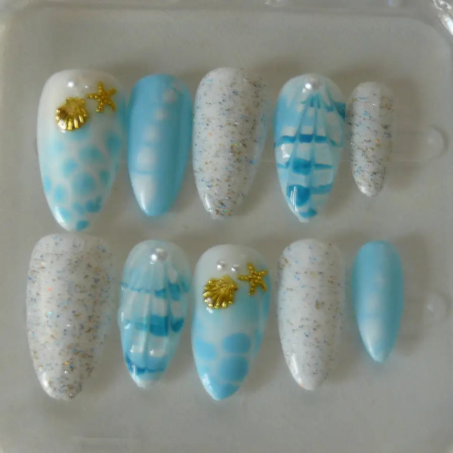 faux ongles estivales, aux allures de la plage, blanc bleu et paillettes viennent sublimer ces press on nails. réhaussés d'étoiles de mer.