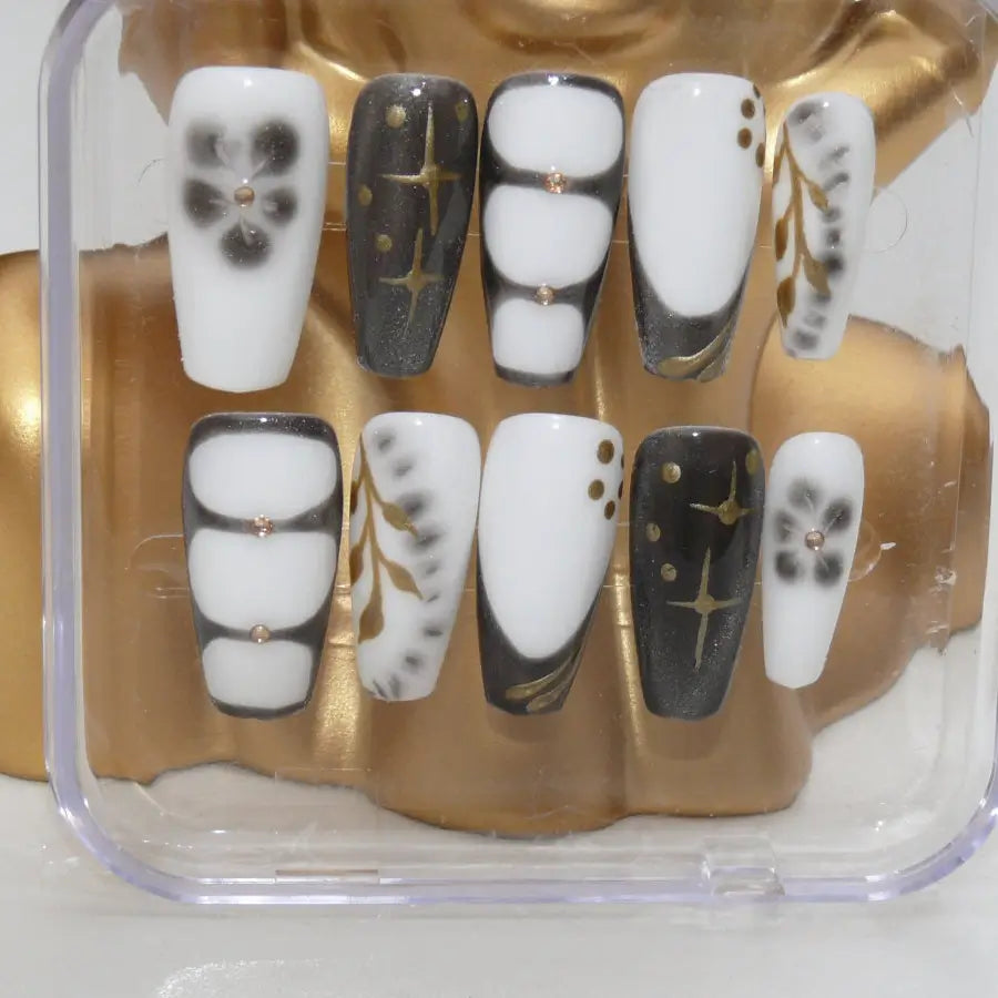 Vue détaillée des faux ongles parisian noir et blanc ornés de strass et d'étoiles dorées
