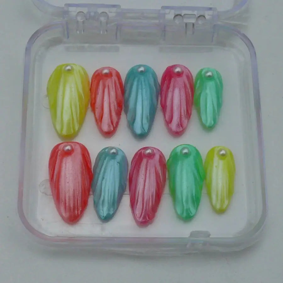 faux ongles aux couleurs estivales, nacrés et réhaussés d'une perle pour rappeler la plage