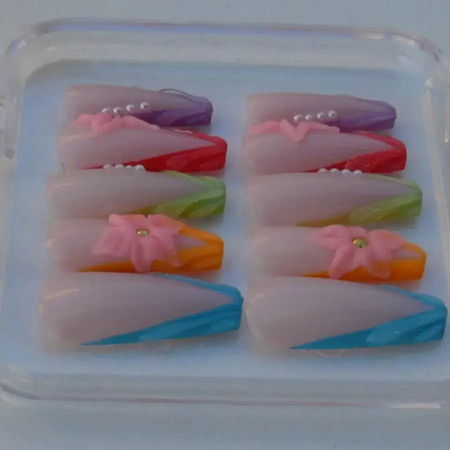 Faux ongles aux couleurs de l'arc en ciel sur une base nude orné de fleurs 