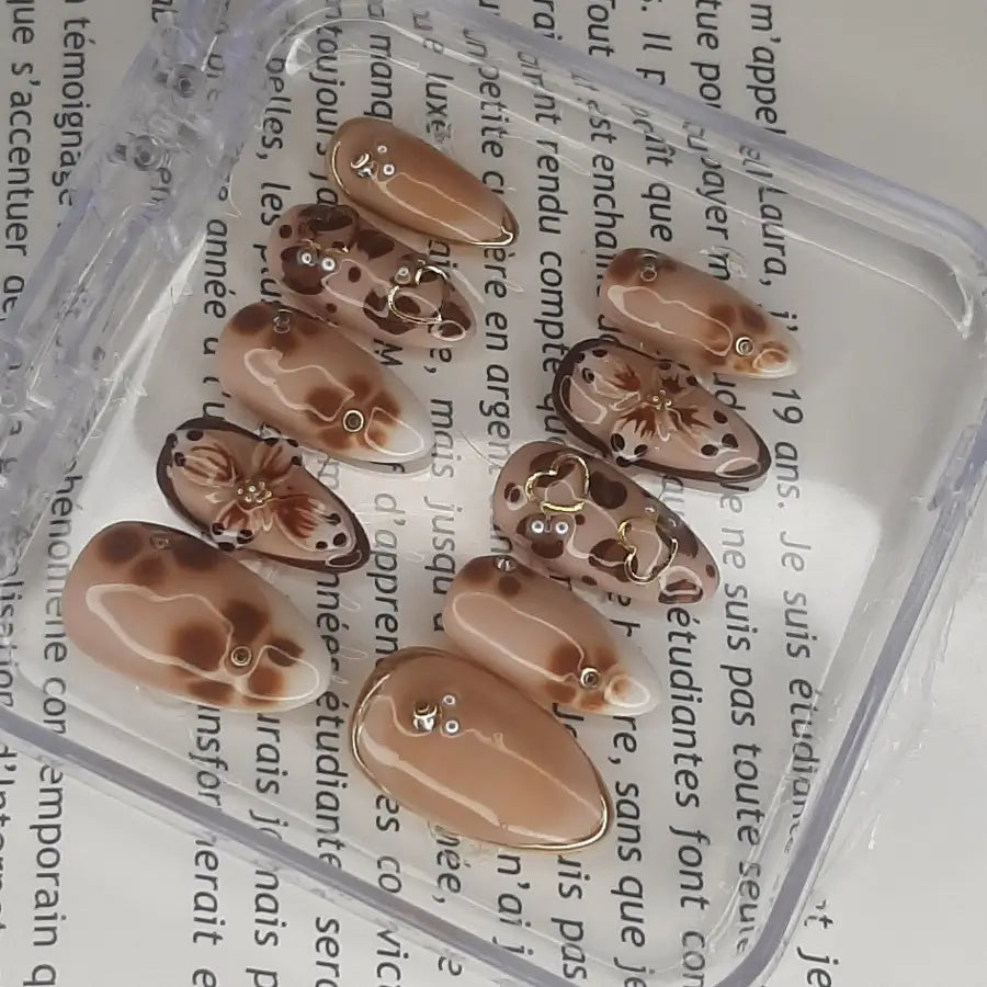 Golden elegance sont des faux ongles de forme amande, de couleurs marron et doré, french blanche et fleurs 3D