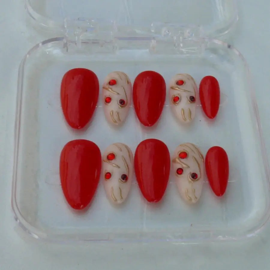 Rouge et blanc, ces faux ongles ornés de strass et doré à l'or fin