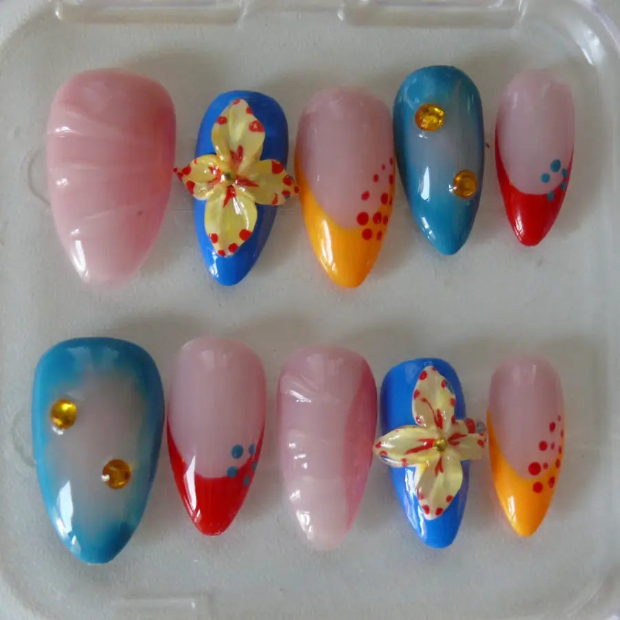 Partez à Hawaï, sous les tropiques avec ces faux ongles très colorés de bleu orange rouge sur une base nude réhaussé de fleurs 3D