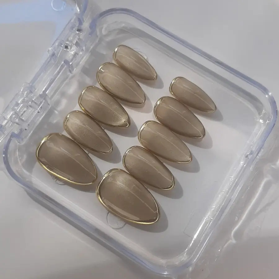 Faux ongles qui captent la lumière et les reflets couleur champagne, vernis cat eyes. Faits main en France, forme Amande