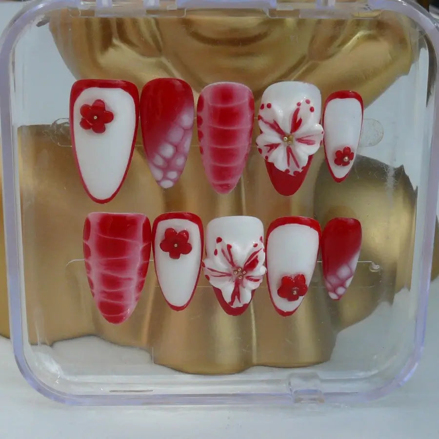 Sur une base blanche, le rouge s'impose, des fleurs viennent sublimer ces faux ongles