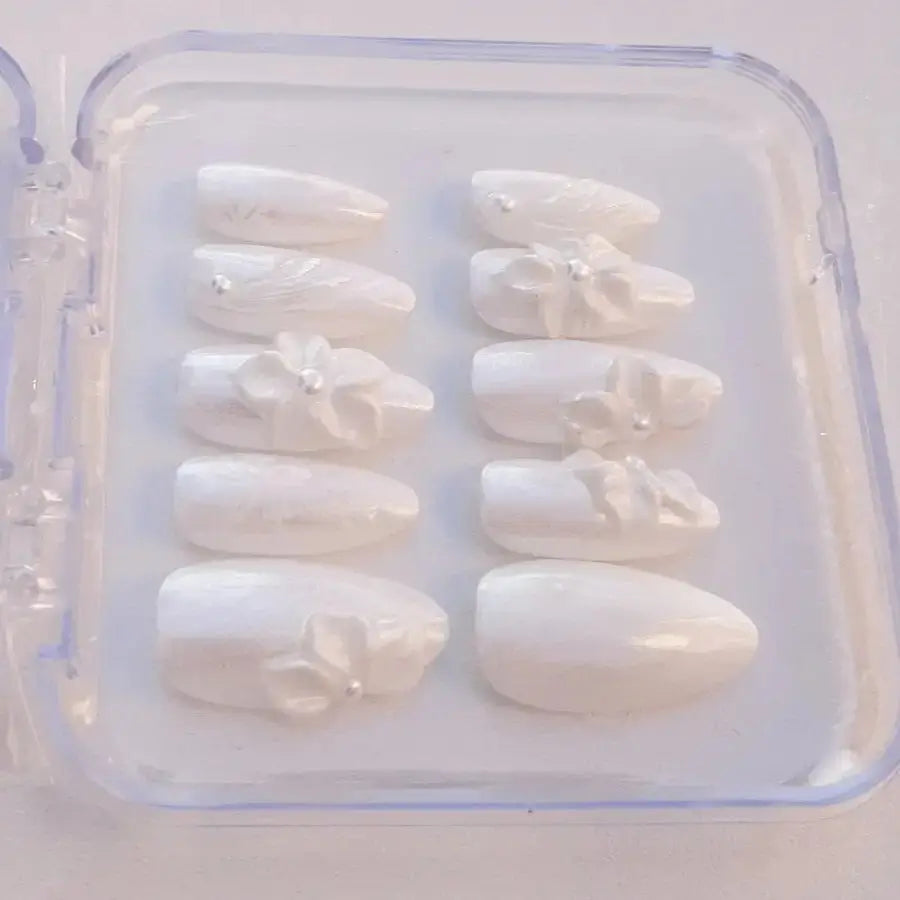 faux ongles d'un blanc pur et nacré ornés de fleurs blanches 3D et perles