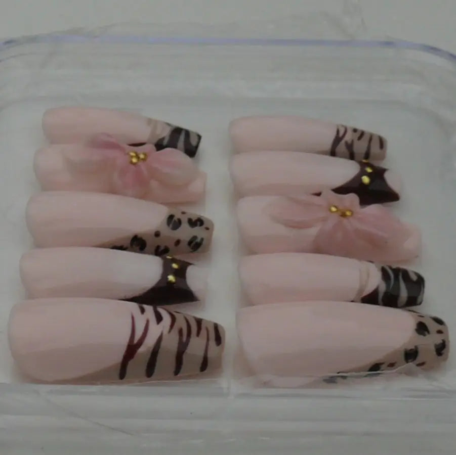 faux ongles aux allures félins réhaussés de fleurs 3D et strass sur une base nude rosée