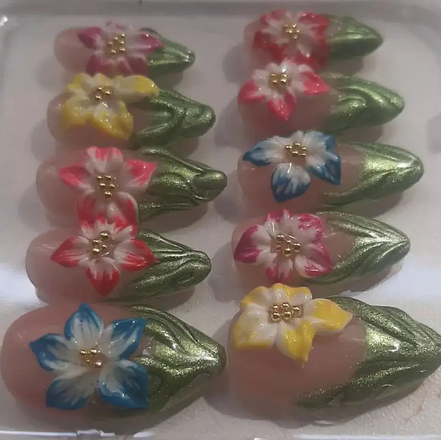 Press-on Capucine vu de profil montrant l'épaisseur et la forme amande des ongles, avec les motifs floraux artistiques en relief et les finitions dorées scintillantes