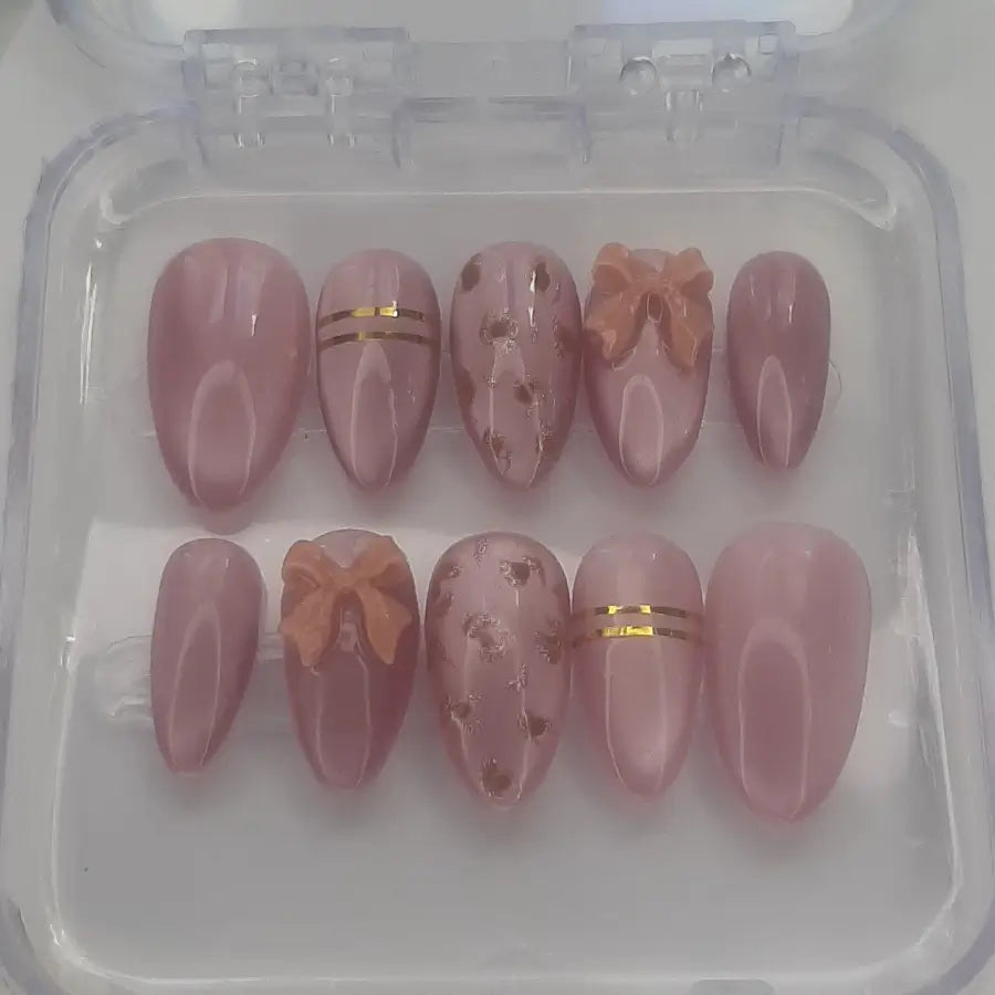 Faux ongles roses cat eyes, réhaussés de noeud 3D, d'un design léopard doré