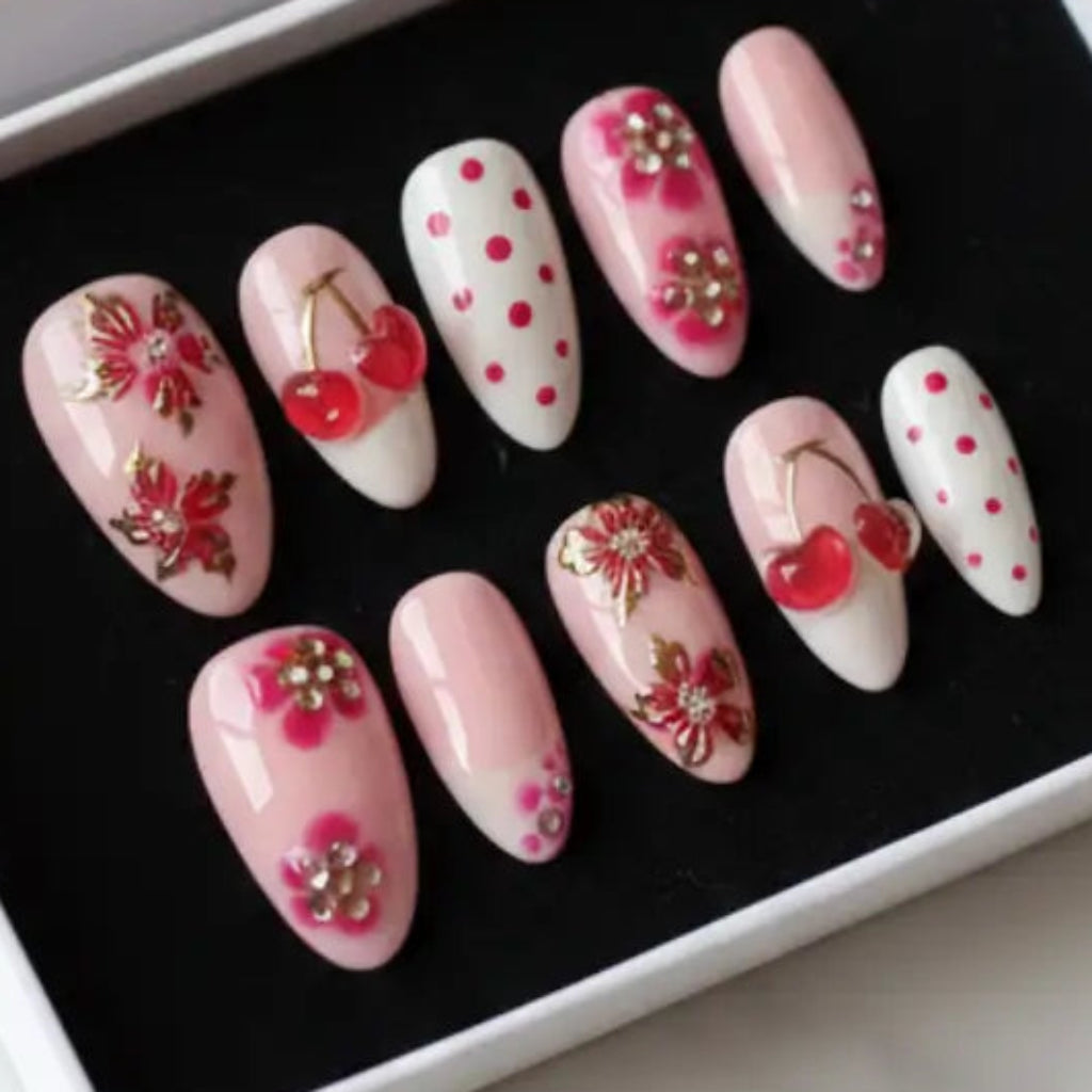 Faux ongles réutilisables "Cherry Love" avec motif cerises rouges sur base nude élégante, fabrication artisanale française. Livraison rapide