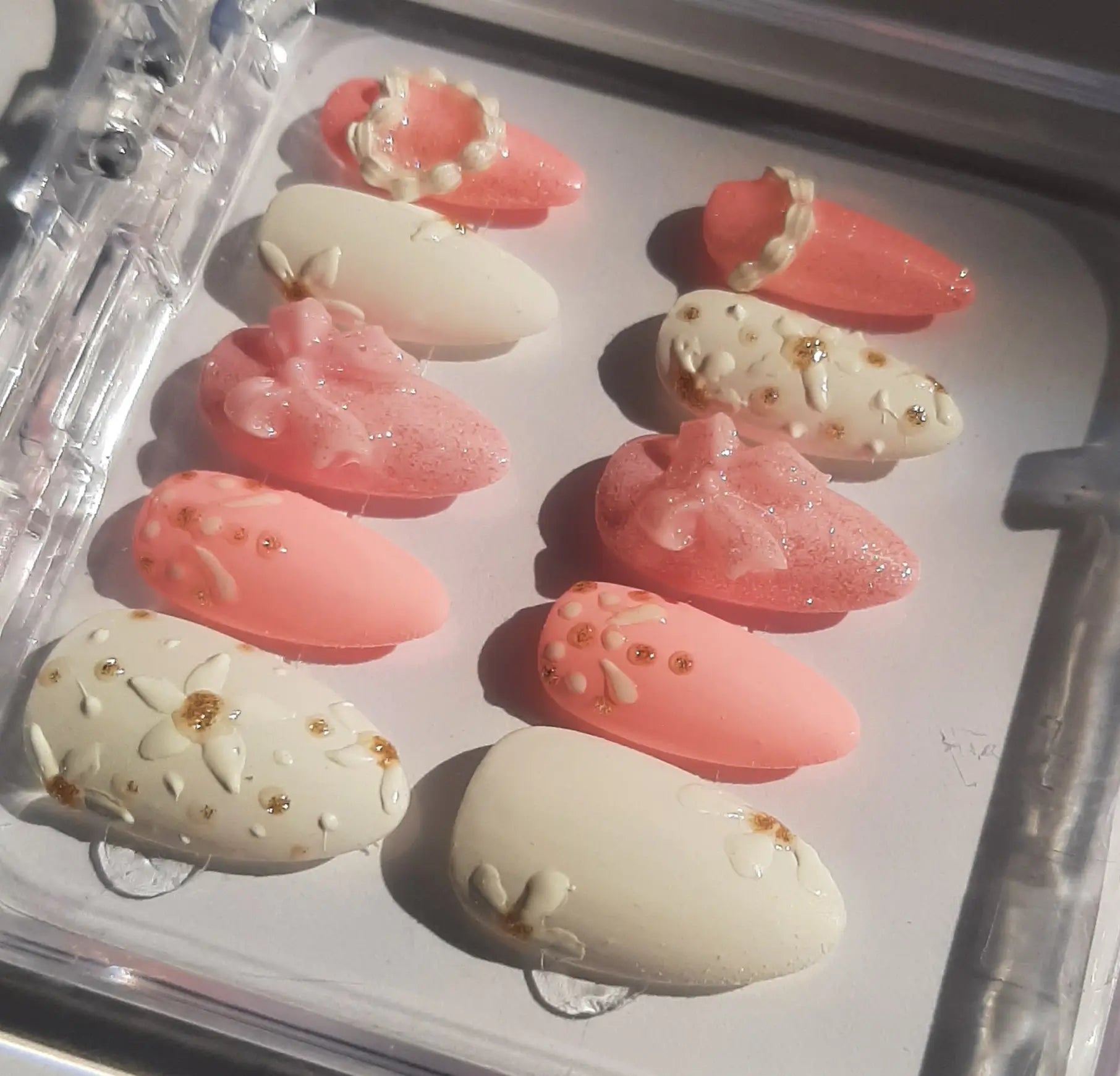 vue de côté révélant les tons nude, rose poudré, ornés de strass dorés et décorations scintillantes, disposés sur fond blanc mariage