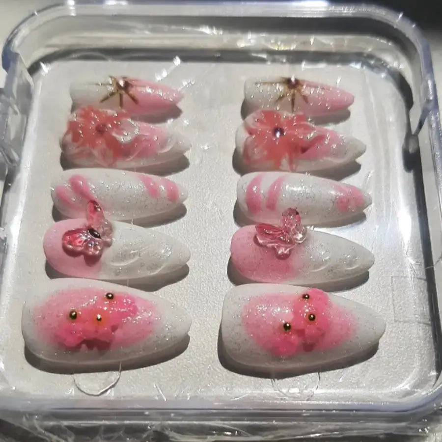Vue détaillée des faux ongles Pink Blossom montrant les fleurs roses en relief avec accents dorés scintillants