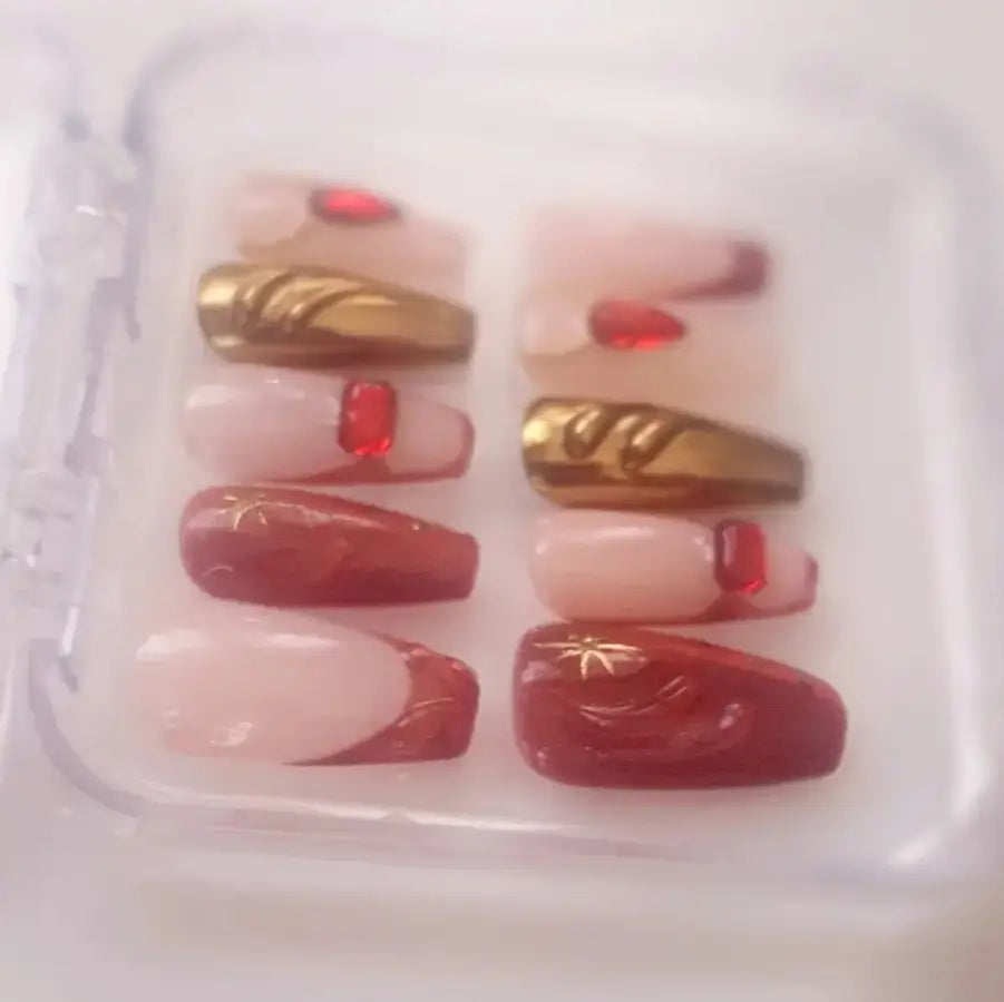 faux ongles sur une base nude, le rouge cat eyes s'impose avec un doré magnifique et des strass