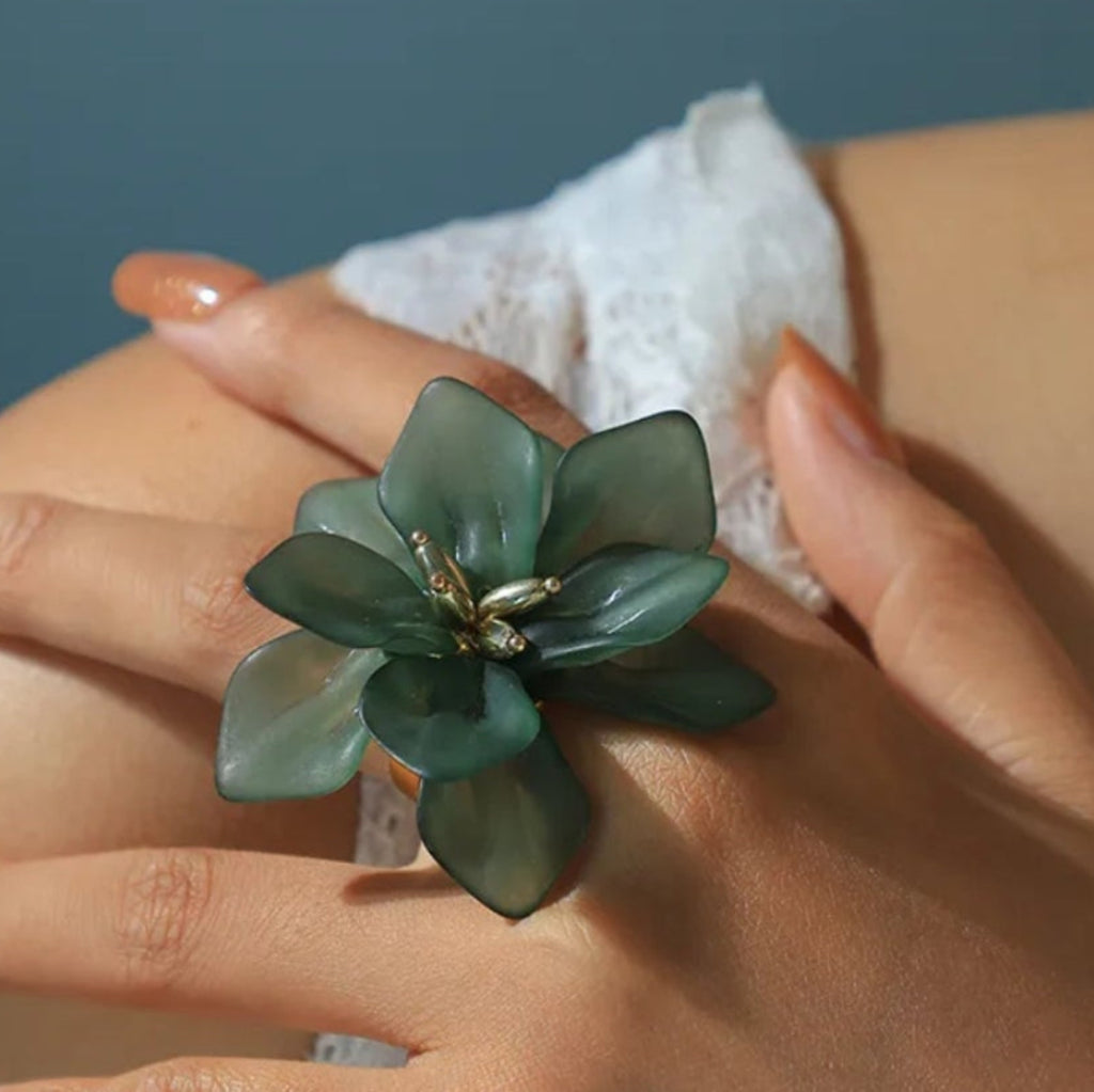 Bague fleur romantique en résine translucide verte portée au doigt, détails dorés au centre
