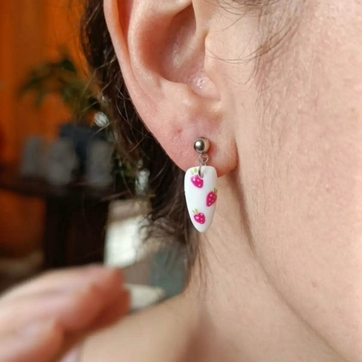 Boucles d'oreilles pendantes en forme d'ongle, fond blanc avec motifs fraises roses, portées à l'oreille — Nail'Style