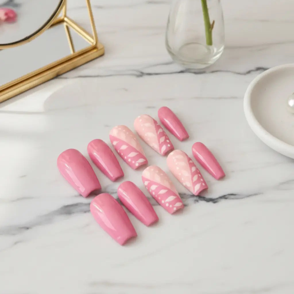 Set de faux ongles réutilisables Candy en dégradé rose poudré et rose vif avec nail art floral, disposés sur marbre blanc.