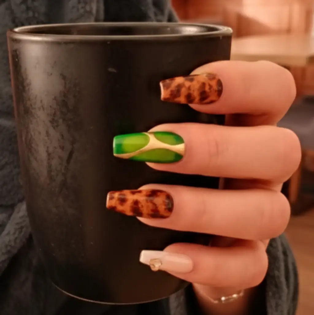 Faux ongles press-on Green Tortoise portés : motif écaille vert émeraude et tortoise marron, forme coffin avec accents dorés.
