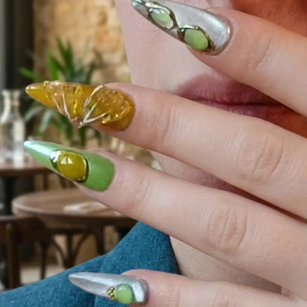 Détail faux ongles Jade Ambert - nail art stiletto avec pierres semi-précieuses vertes et jaunes, effet cat eye et embellissements dorés - qualité premium.