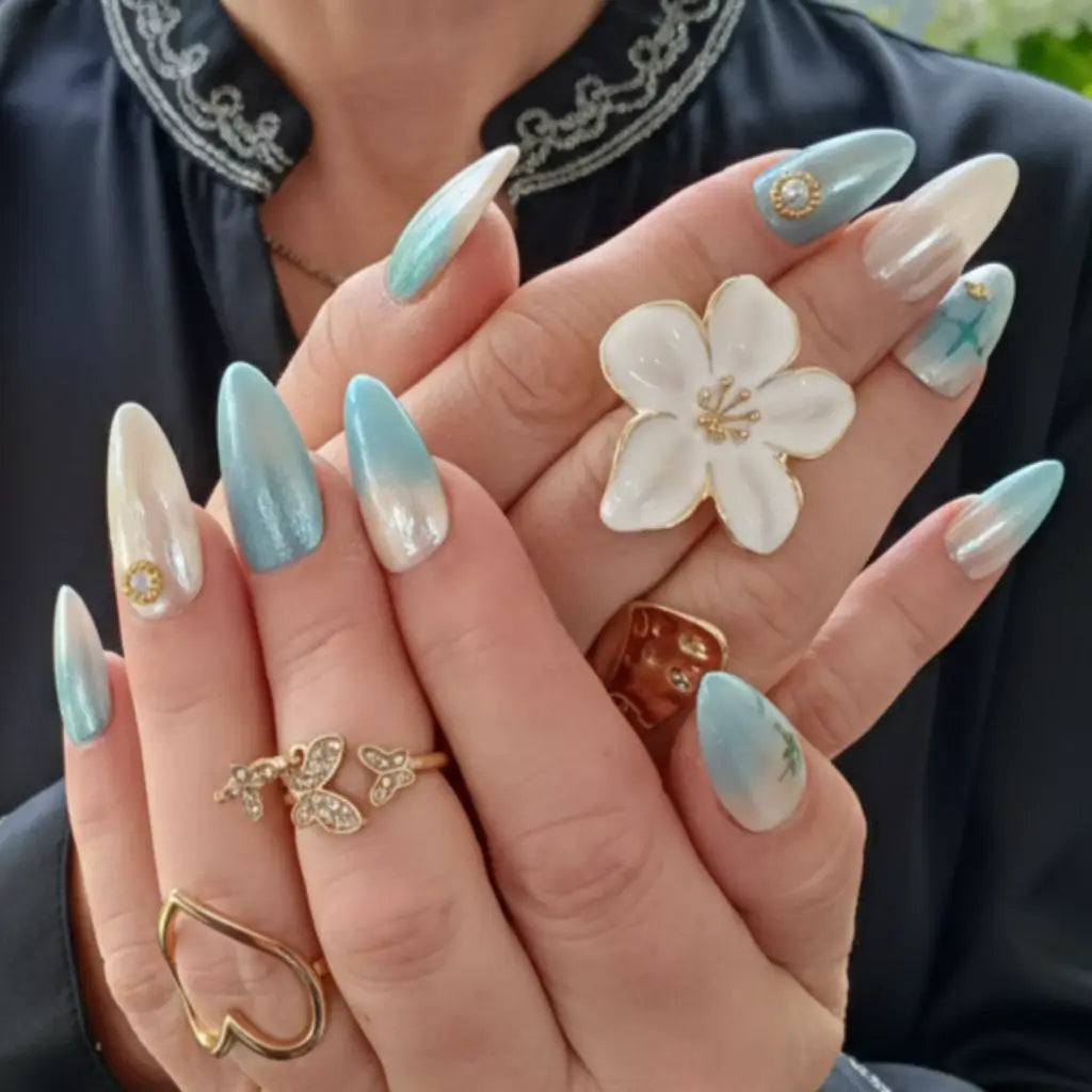 Press-on nails Perle de Ciel fabriqués en France - vue portée avec bagues dorées.