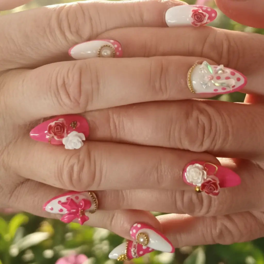 Manucure press-on Pink Romance portée : ongles rose et blanc avec roses 3D blanches, perles et pois dorés.