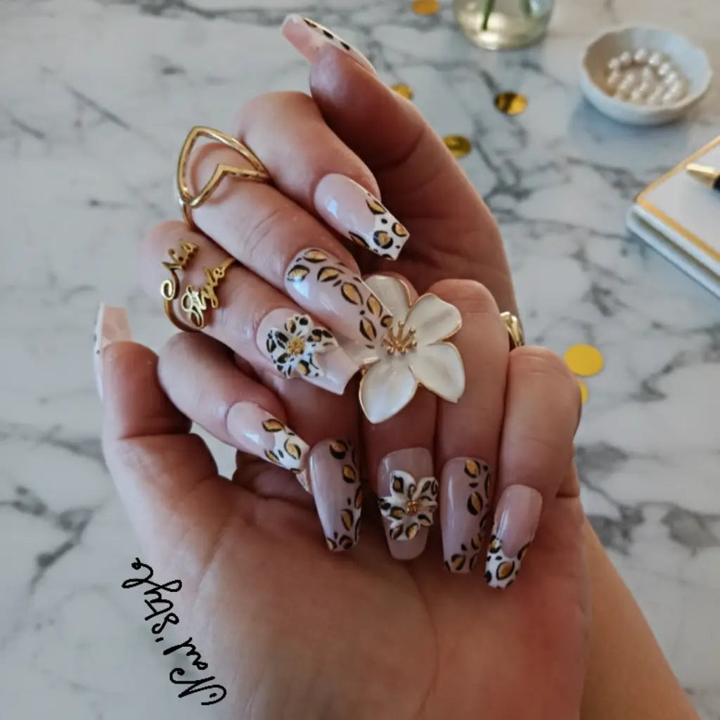 Press-on nails coffin moyen Safari Petals, nail art léopard doré sur base nude avec bagues cœur et fleur - manucure express luxe.