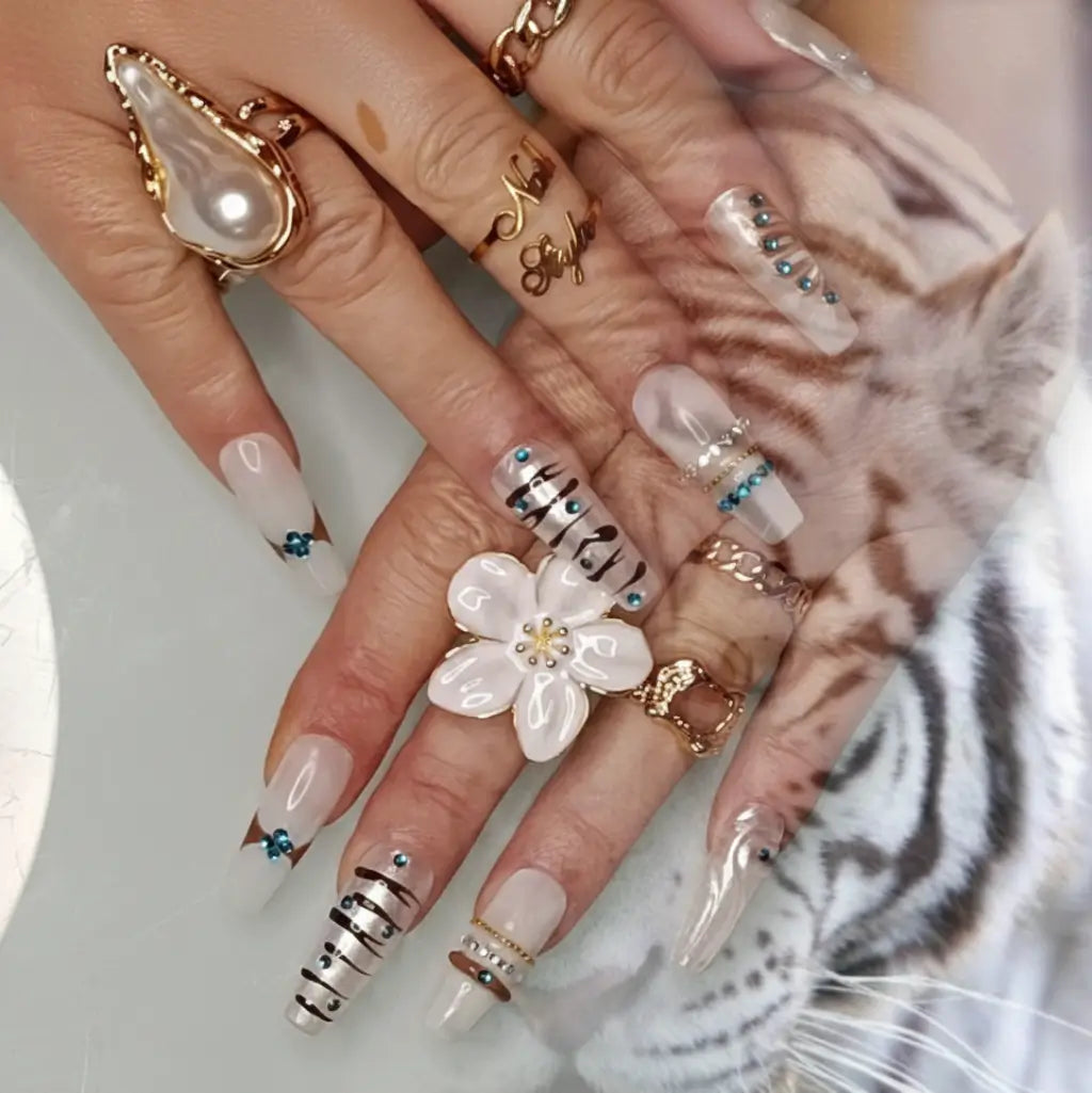 Faux ongles blanc tigre portés avec bague fleur