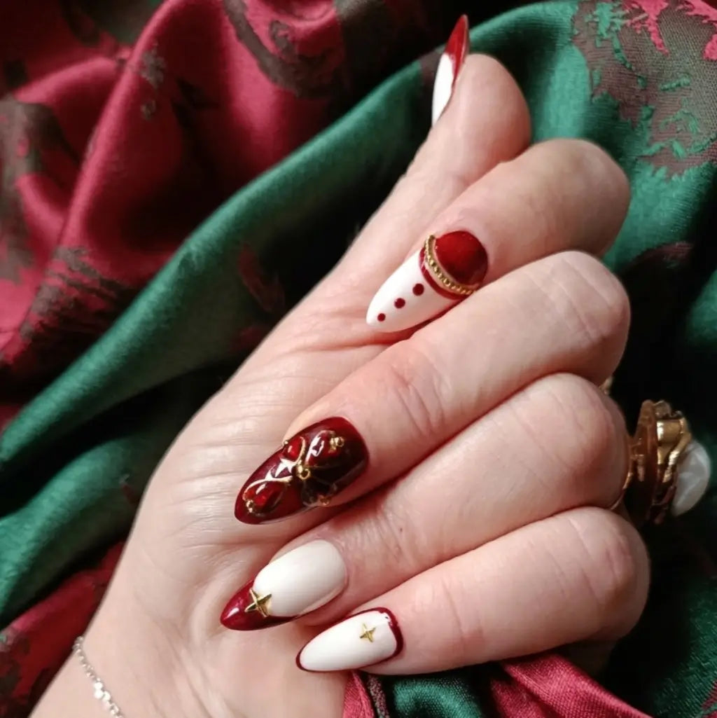 Faux ongles press-on Velvet Rouge – forme amande, bordeaux et blanc avec ornements dorés et croix catalane, fabriqués en France.