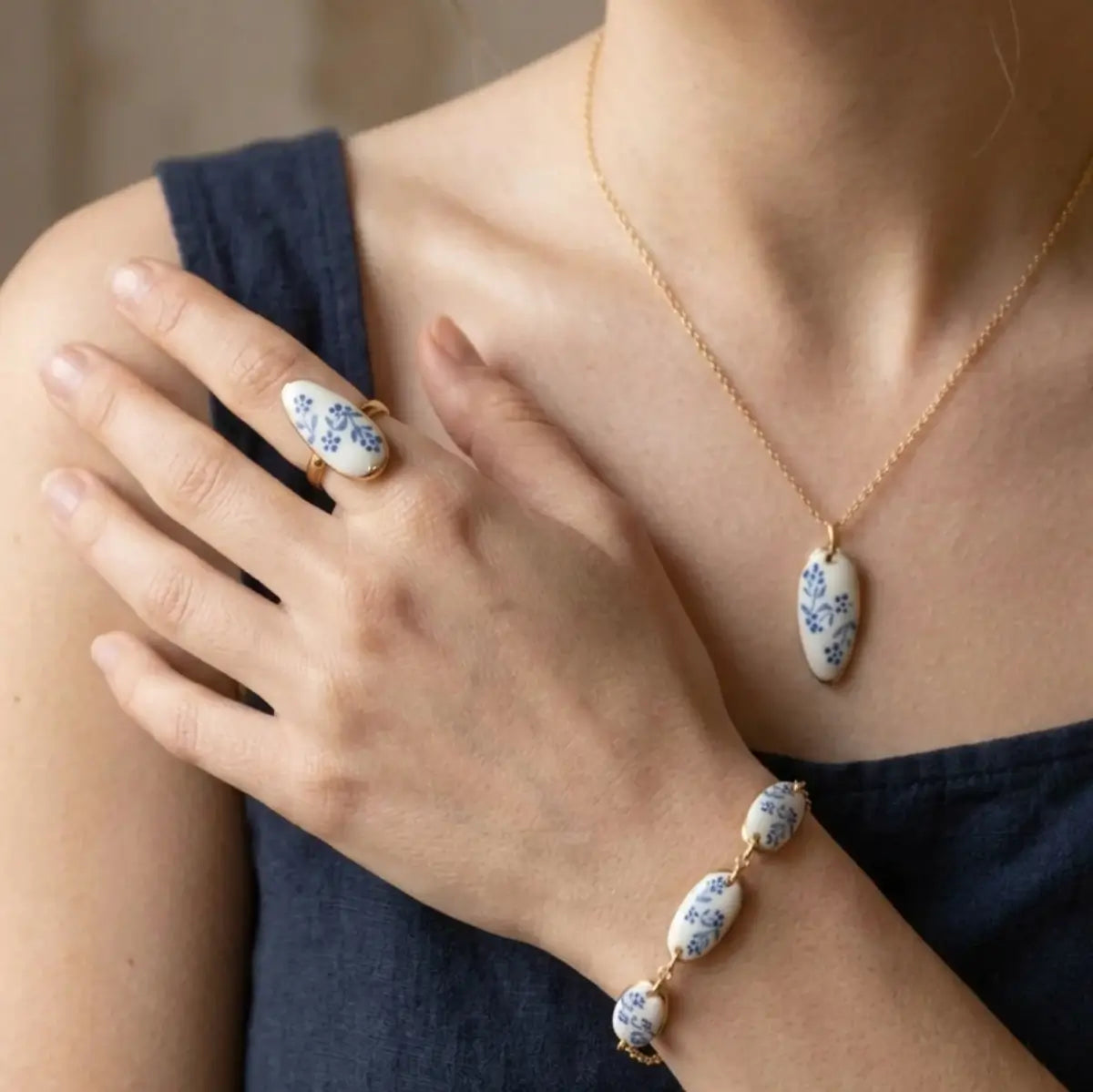 Parure bijoux nail art fleurs bleues – bague, bracelet et collier assortis portés par un modèle.