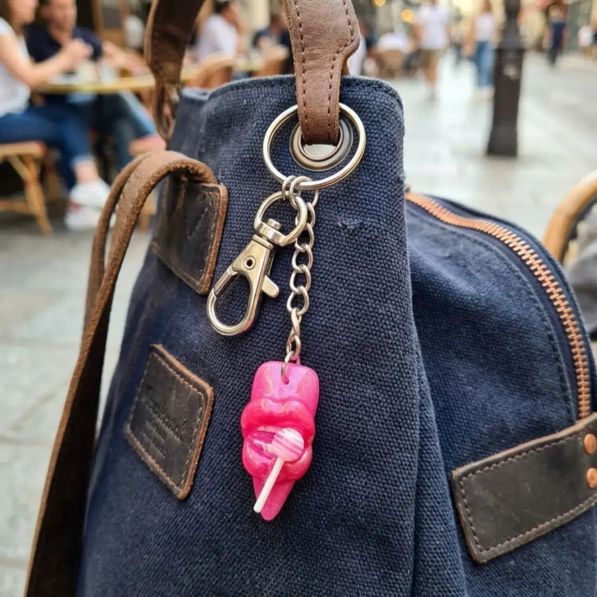 Porte-clés résine artisanal en forme de lèvres roses tenant une sucette, accroché à un sac en toile bleu marine — bijou de sac Candy Lips Nail'Style