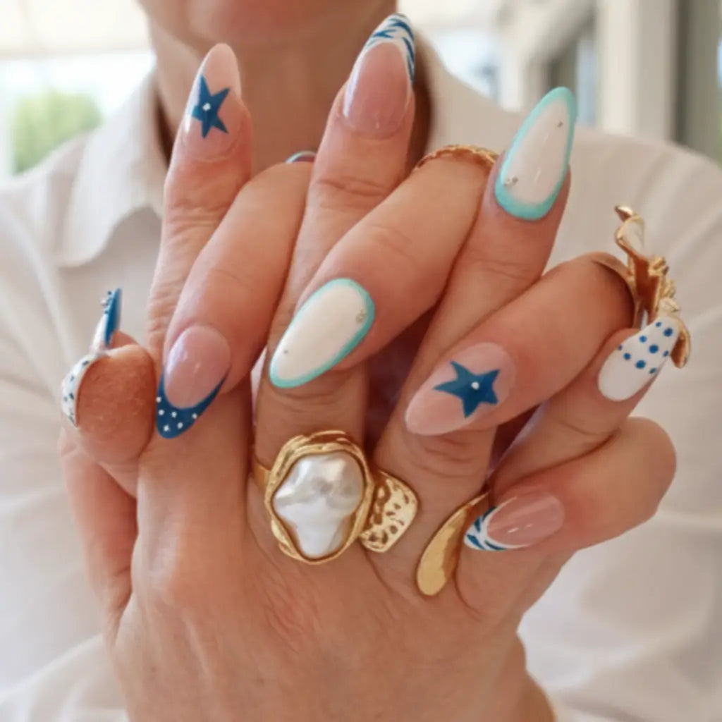 Manucure press-on Riviera Bleue portée, design nautique bleu marine et turquoise sur ongles forme amande, bijoux dorés.