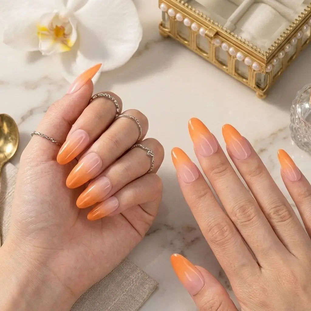 Press-on nails Peach Glow Made in France portés sur mains avec bagues chaînettes, dégradé rose orange abricot fabrication artisanale française.