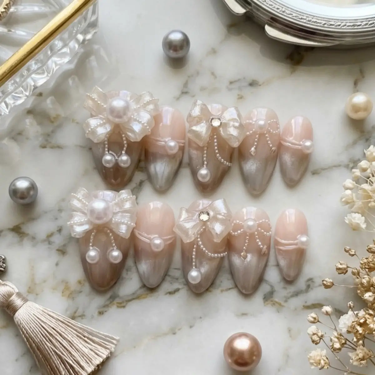 Faux ongles press-on en amande, finition cat eye nude rosé, ornés de nœuds en organza nacré, chaînettes de perles et strass