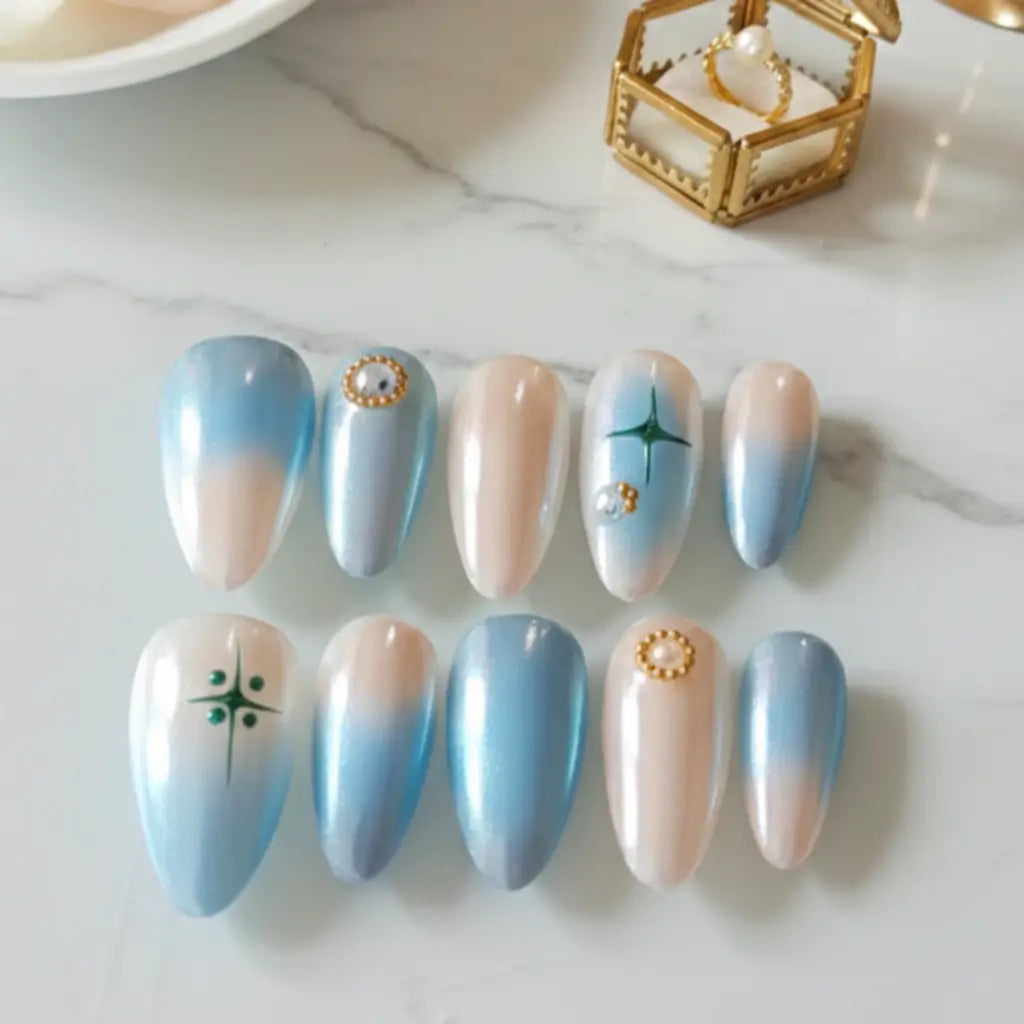 Faux ongles Perle de Ciel forme amande bleu ciel et nude avec détails dorés. Made in France. Forme Amande.