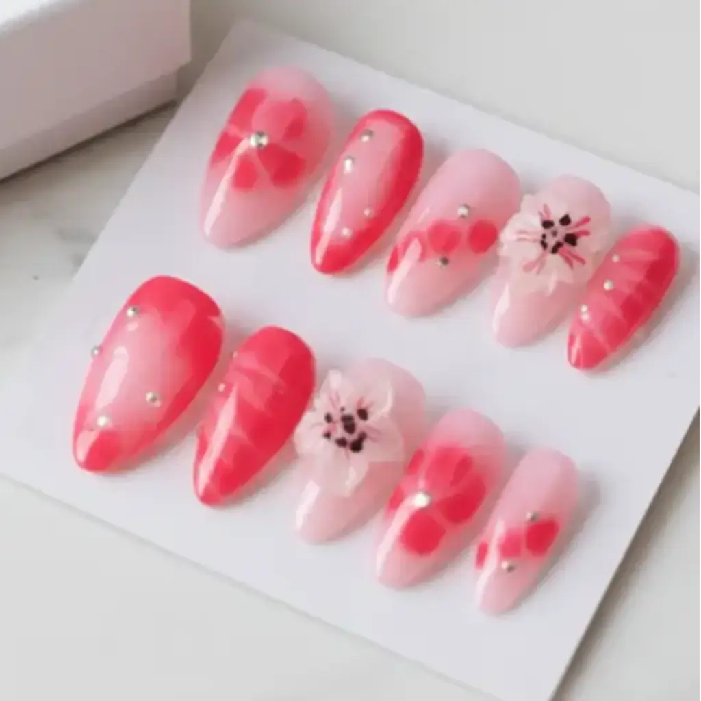 Faux ongles réutilisables Kaymie rose corail avec fleurs 3D et strass dorés sur fond nude