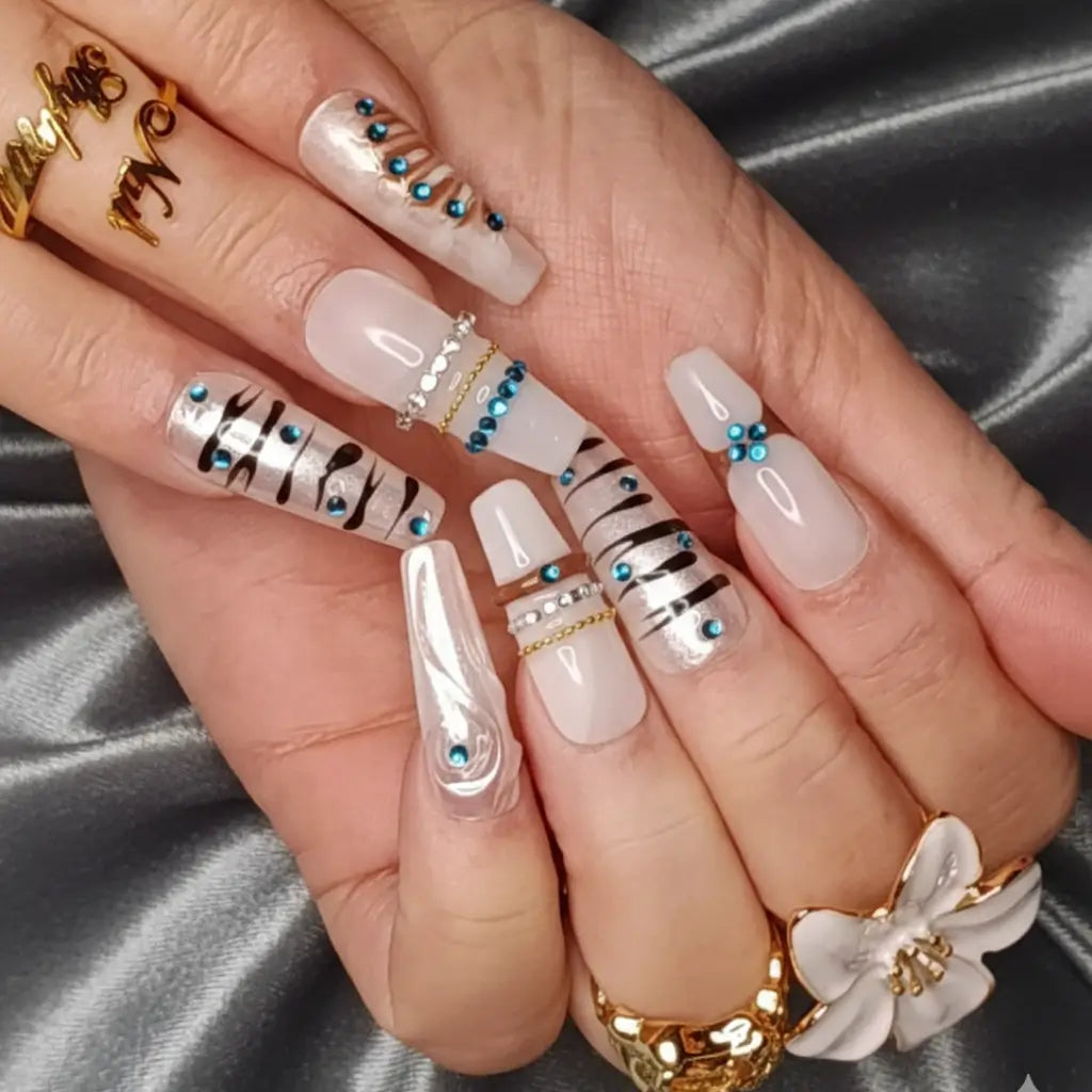 Faux ongles réutilisables blanc à motifs zèbre et strass turquoise portés avec bagues dorées - Nail'Style