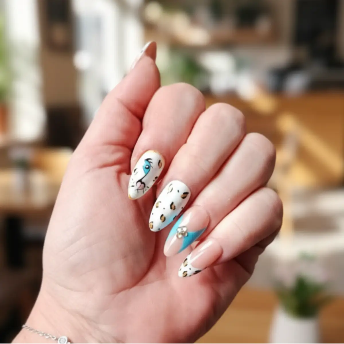 Faux ongles press-on amande motif tigre blanc aux yeux bleus, taches léopard dorées et éclair turquoise avec strass