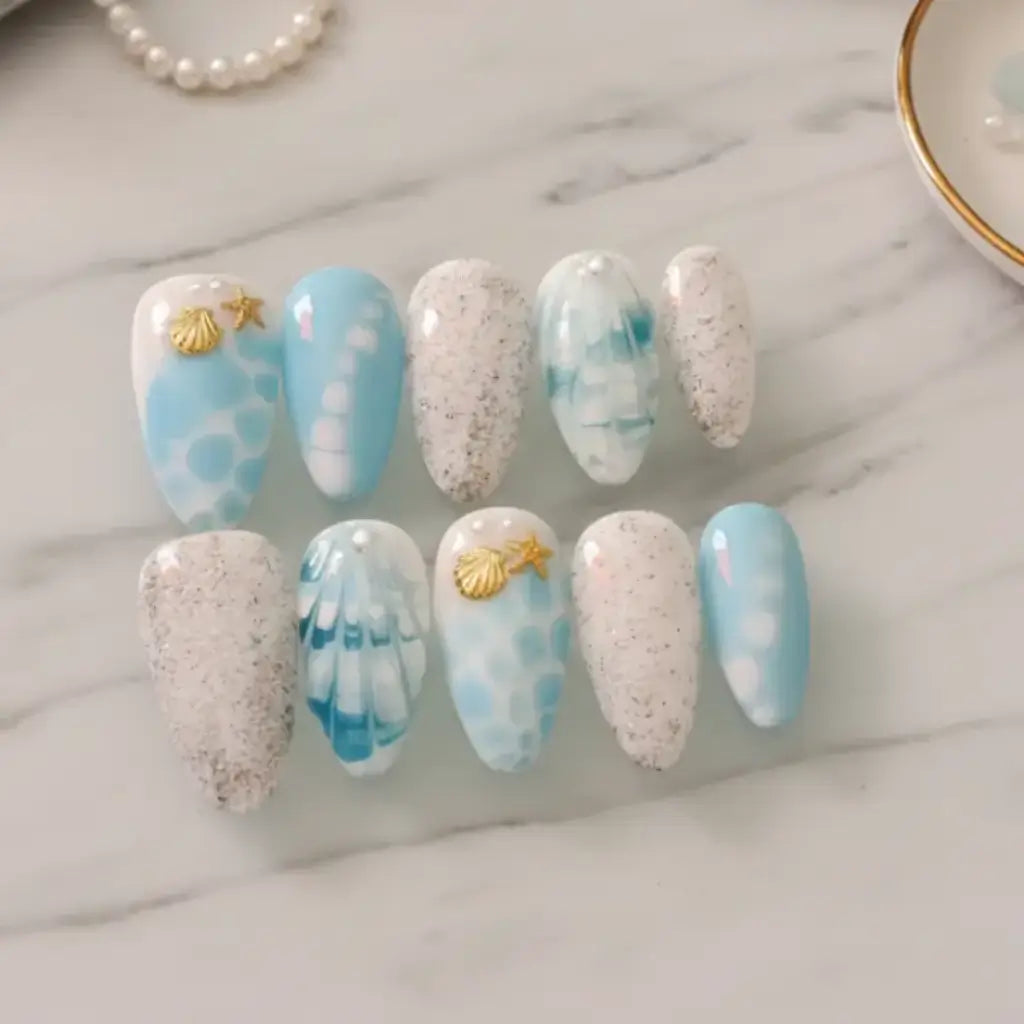 Press-ons Nérina thème marin - bleu azur et blanc avec coquillages dorés et paillettes argentées.